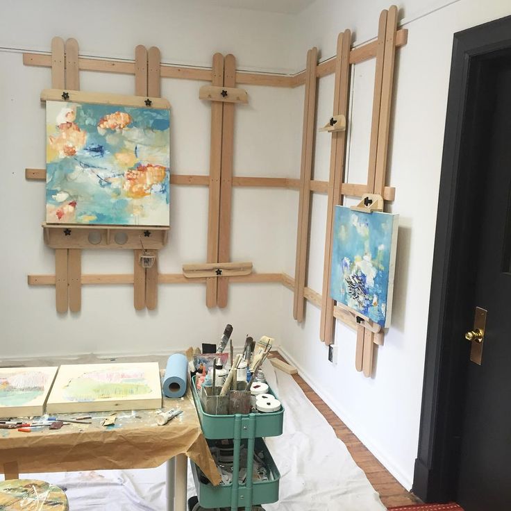 an artist's studio with easels and paintings on the wall