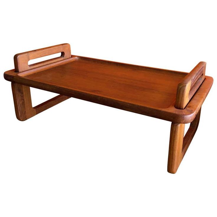 a wooden tray with a handle on the top and legs, sitting on a white background