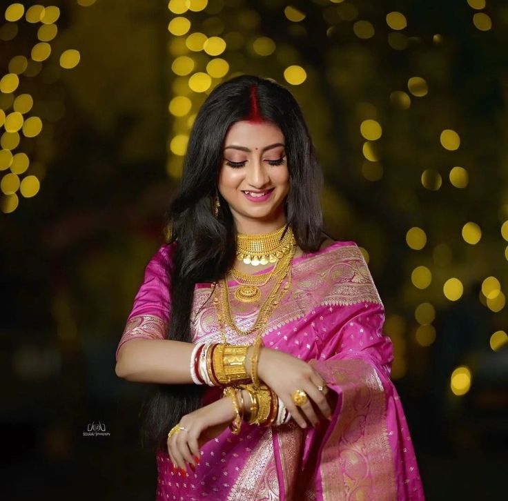 a woman in a pink sari and gold jewelry