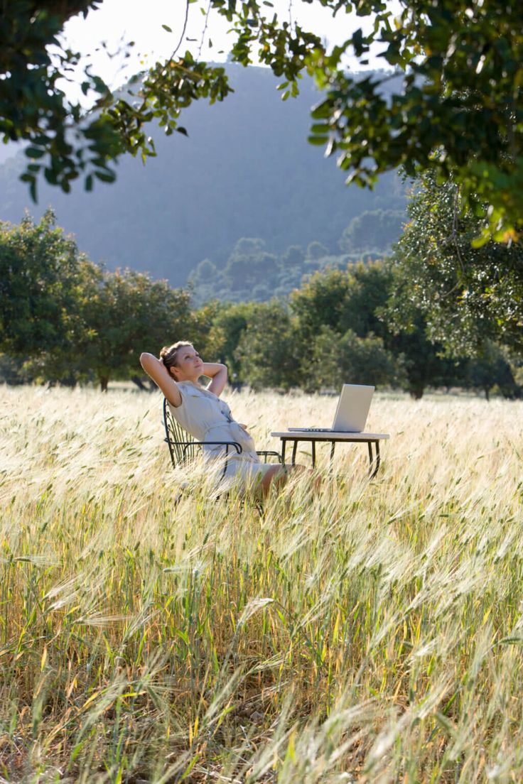 a man sitting in a chair on top of a grass covered field