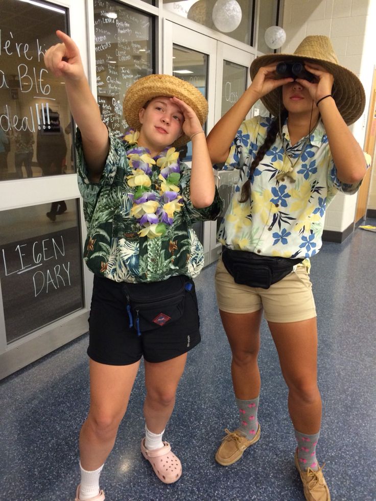 two girls wearing hats and shorts are looking through binoculars