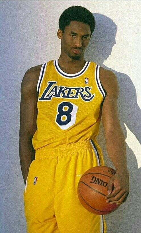 a man holding a basketball standing next to a wall