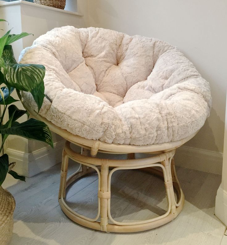 a chair with a cushion on it next to a potted plant in a room