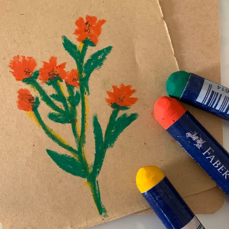 some crayons are laying on top of a piece of paper with flowers drawn on it