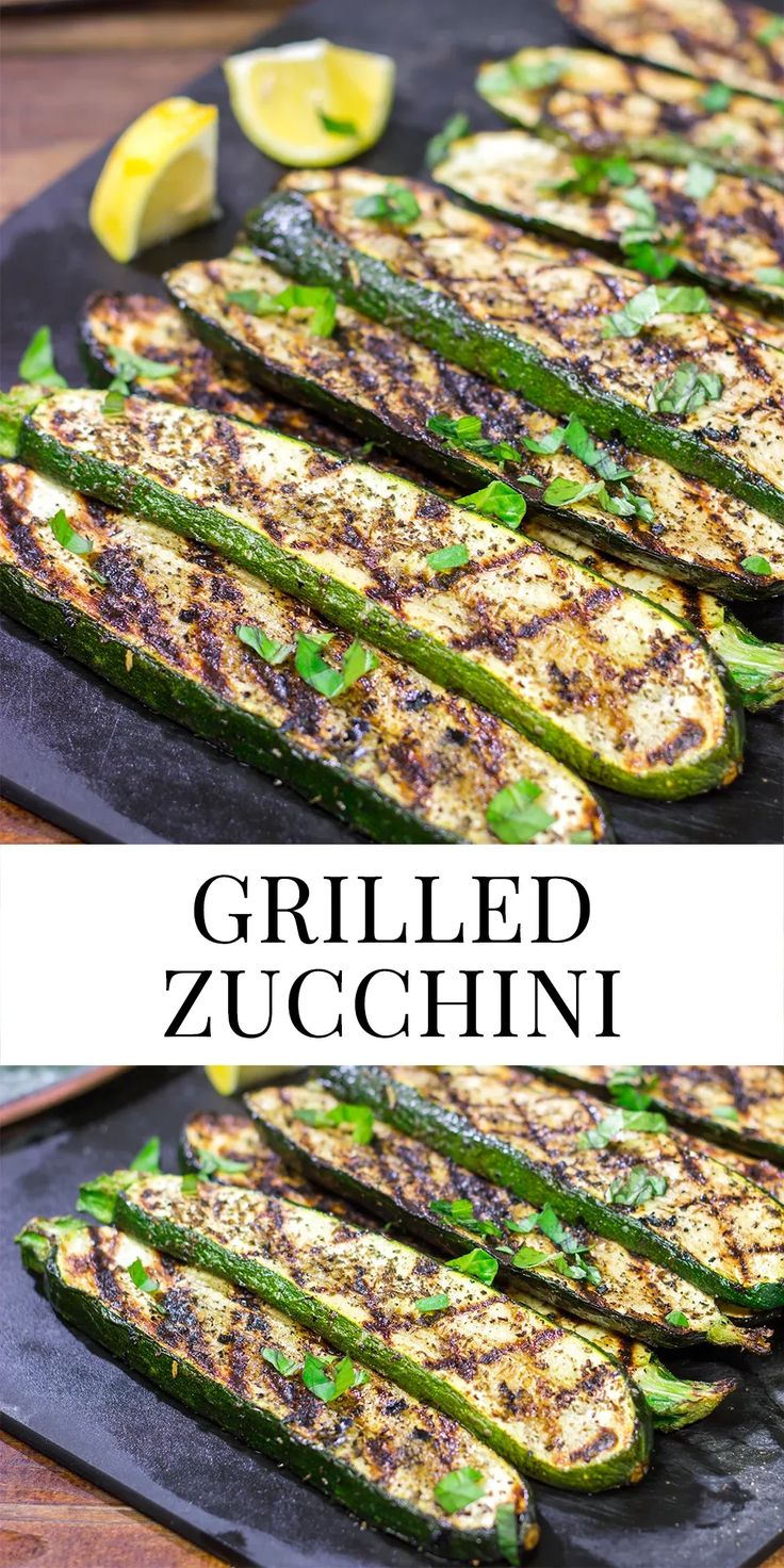 grilled zucchini on a black plate with lemon wedges