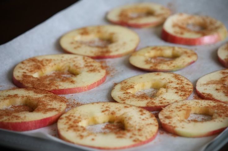 apple slices with cinnamon sprinkled on them sitting in a baking pan, ready to be baked