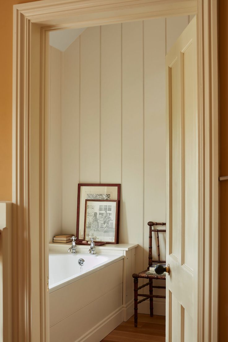 an open door leading to a bathroom with a bathtub and chair next to it