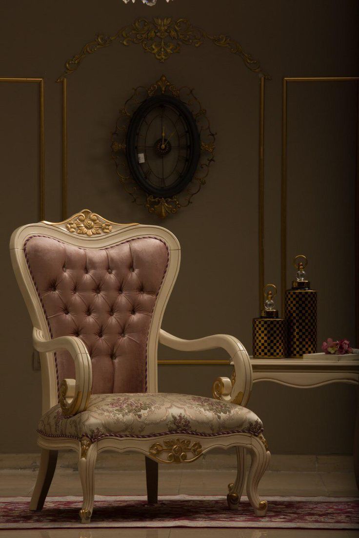 an ornate chair sits in front of a wall with a clock on it's side