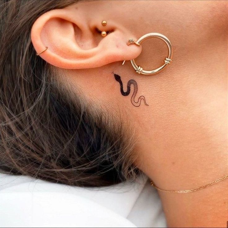 a woman with a tattoo on her neck and behind the ear is a small snake