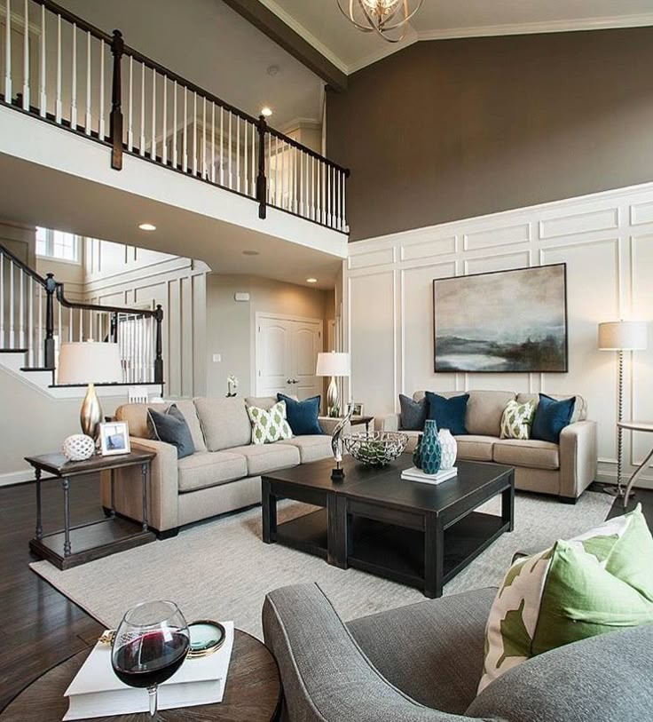 a living room with couches, chairs and a coffee table in front of a staircase