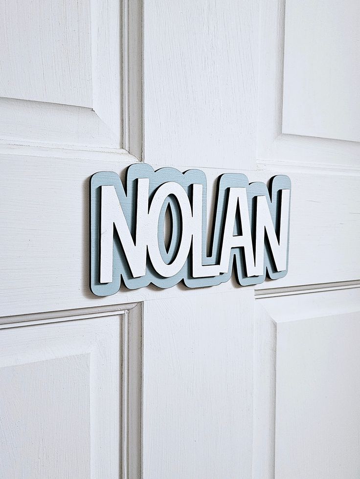 the word nolan is spelled in metal letters on a white door