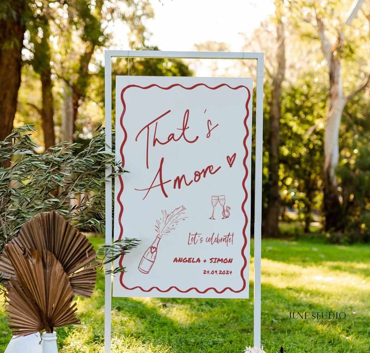 a sign that is in the grass near some flowers and an orange umbrella with writing on it