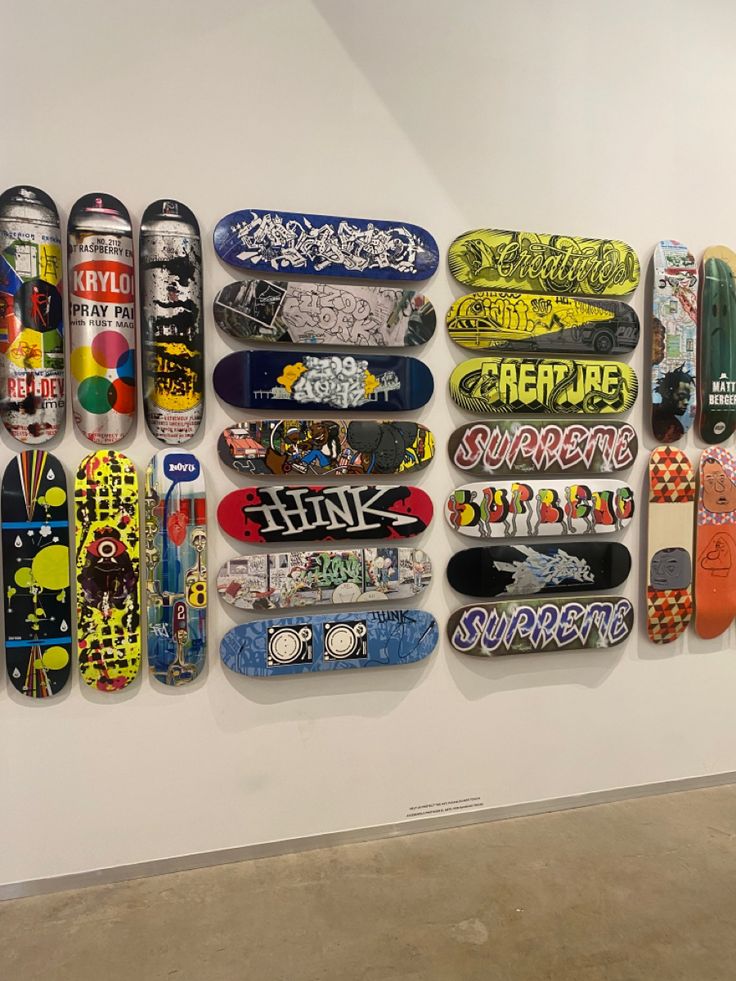 several skateboards mounted to the side of a wall in an art gallery, with graffiti written on them