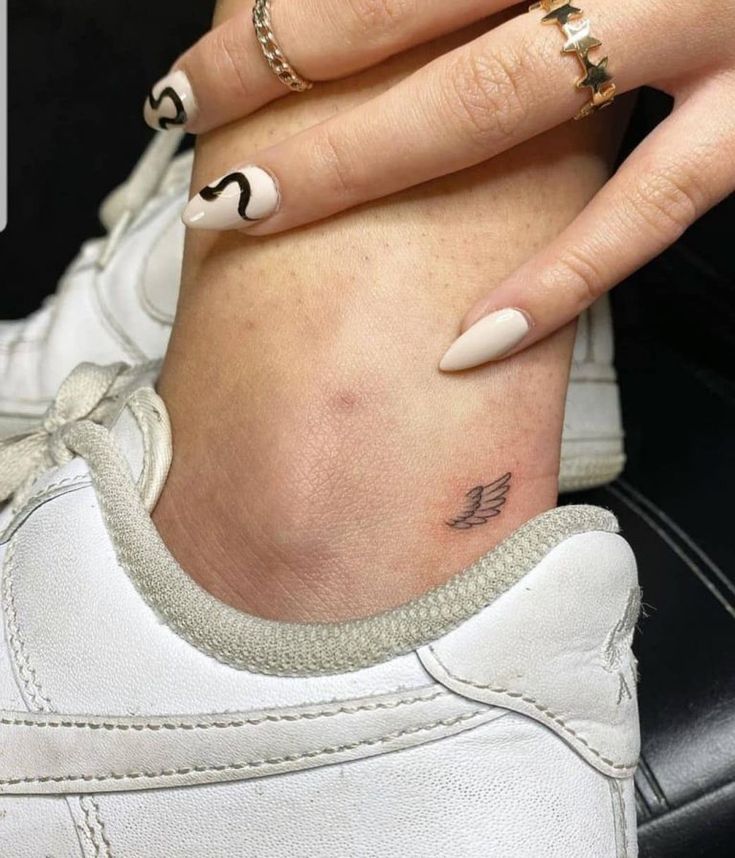 a woman's foot with two rings on it and a small tattoo on her left ankle