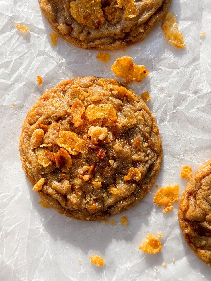 three cookies on top of white paper with orange peels and crumbled edges