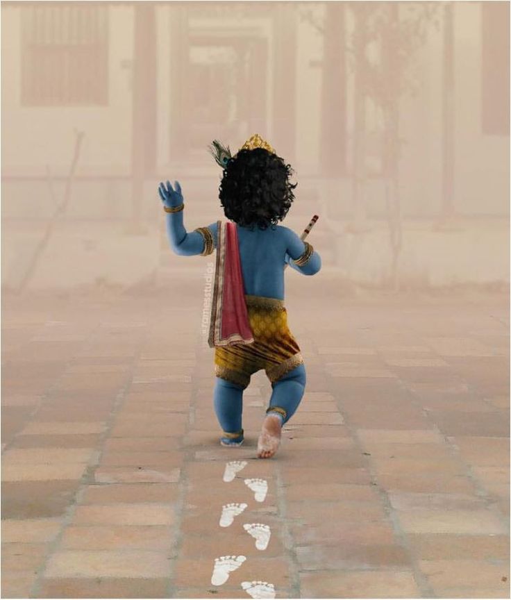 a small child dressed in blue and yellow is standing on the sidewalk with his hand up