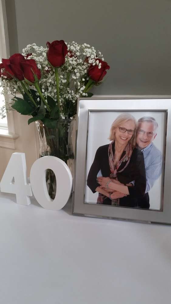 a vase filled with flowers next to a couple's photo and the number forty four