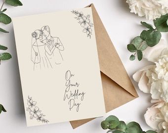 a card with the words your wedding day written on it next to flowers and greenery