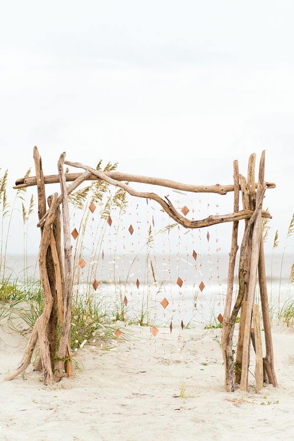 a wooden structure made out of branches on the beach