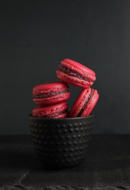 a black bowl filled with red cookies on top of a table