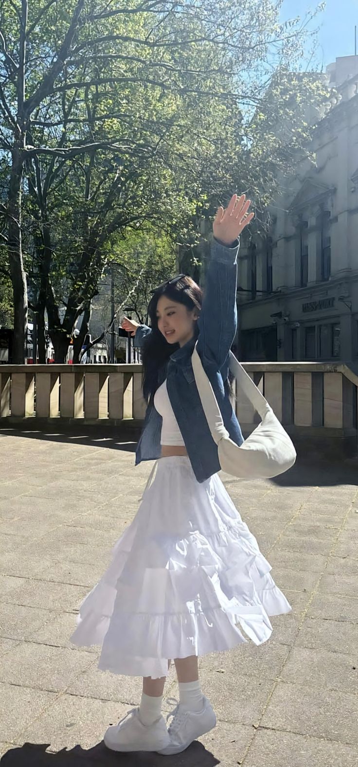 a woman in a white dress and jacket is waving