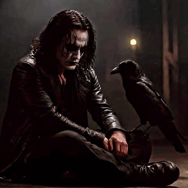 a man sitting on the ground next to a crow