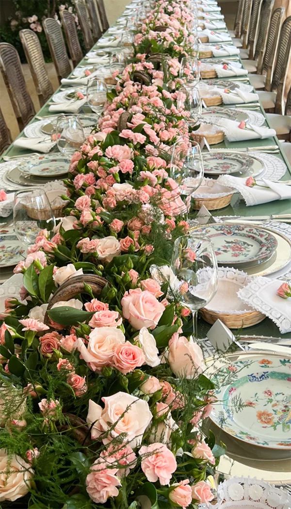 a long table is set with pink flowers and place settings for the guests to sit down