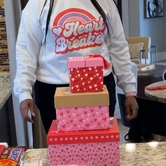 a woman standing in front of a stack of boxes on top of a kitchen counter