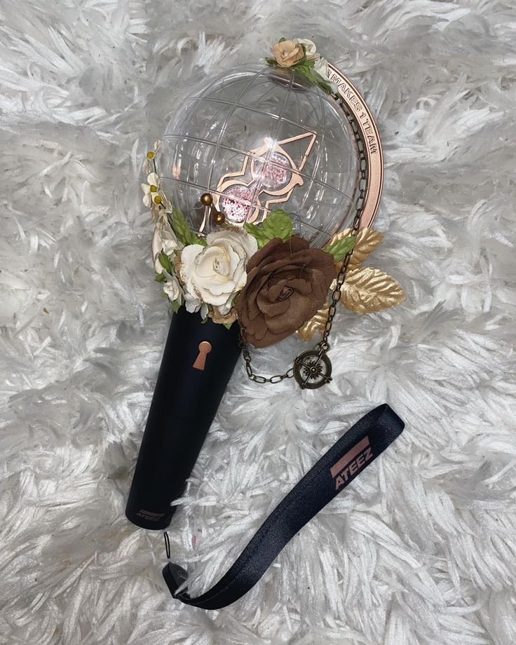 a black vase with flowers on it sitting on a white fur covered floor next to a lanyard