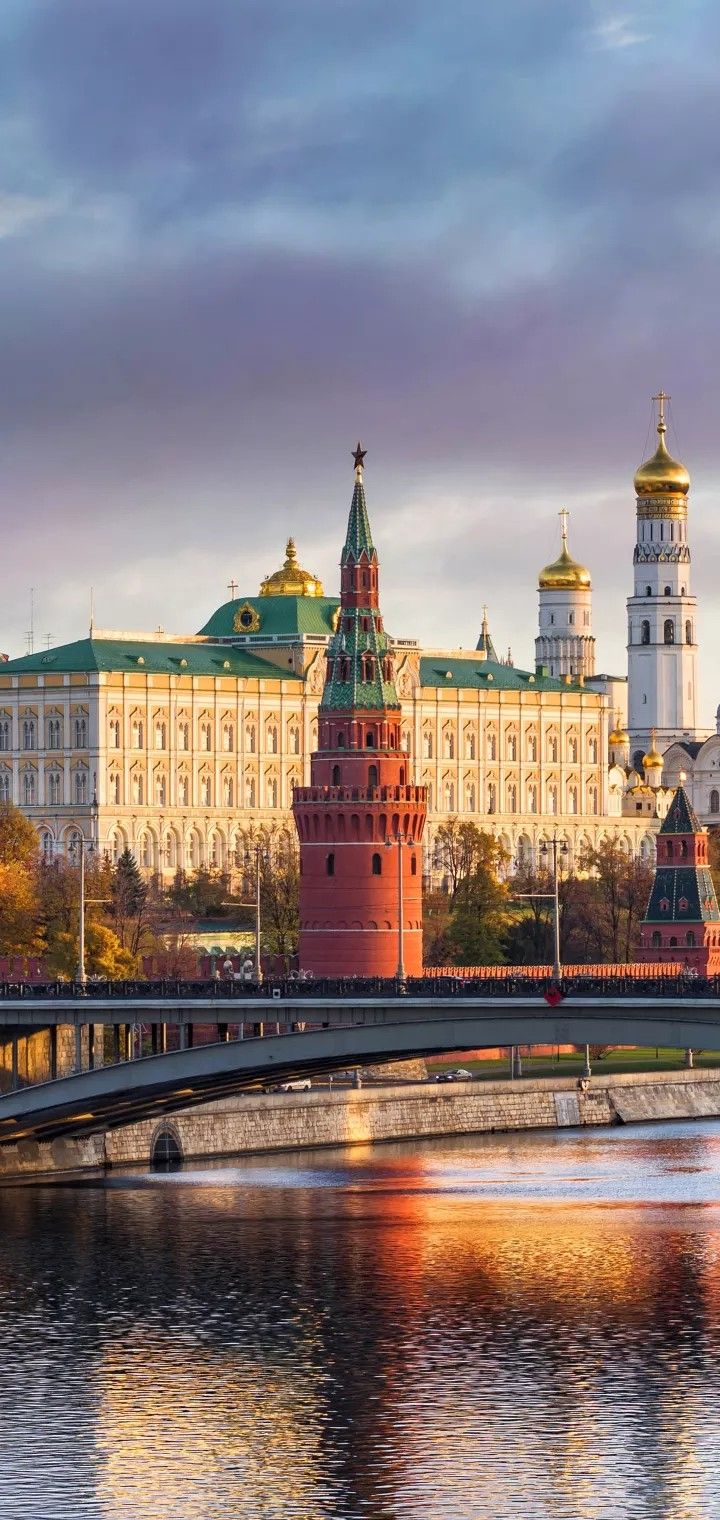 there is a bridge that crosses over the water in front of a large building with towers