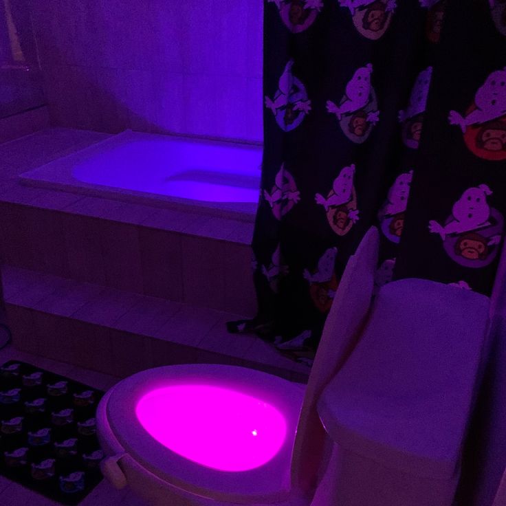 a bathroom with a purple light on the toilet and bathtub next to it is lit up