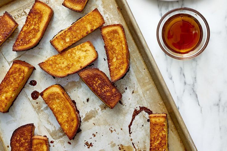 toasted french toast sitting on top of a pan next to a cup of tea