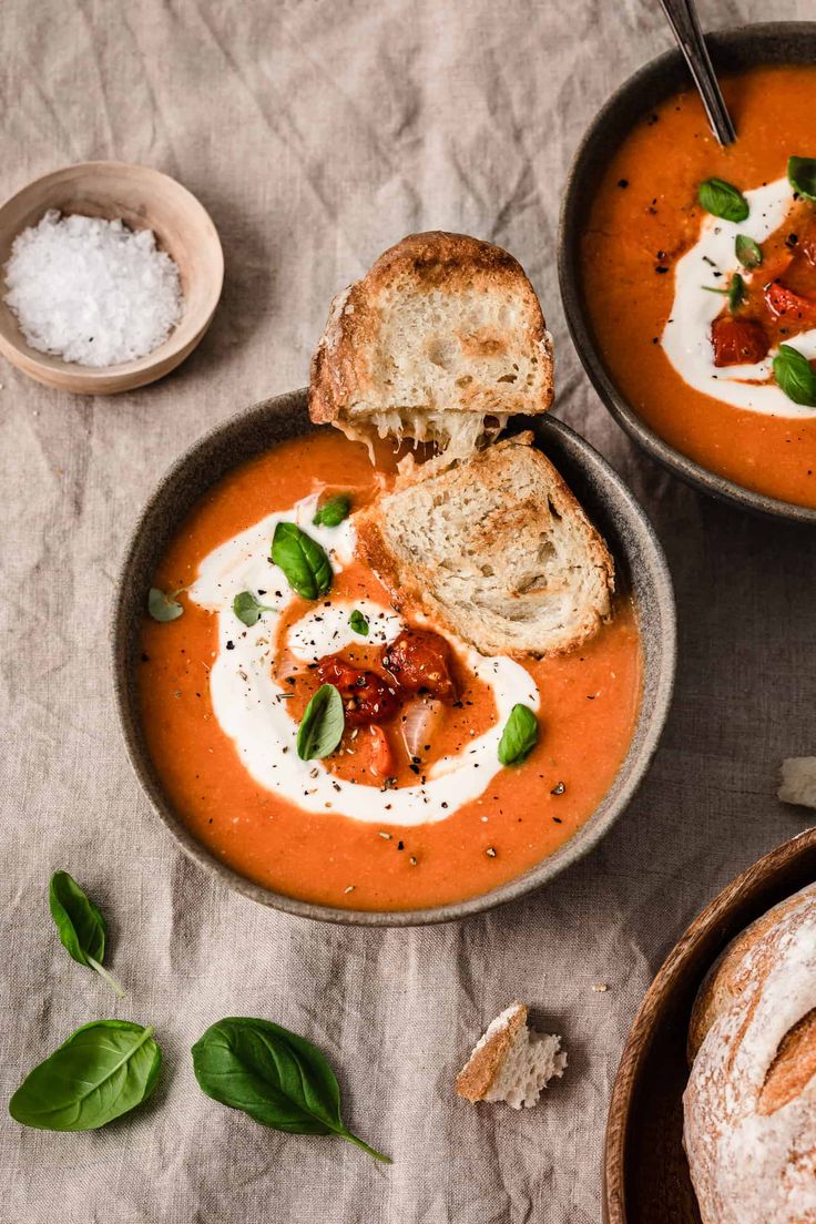 two bowls filled with soup and bread on top of a table