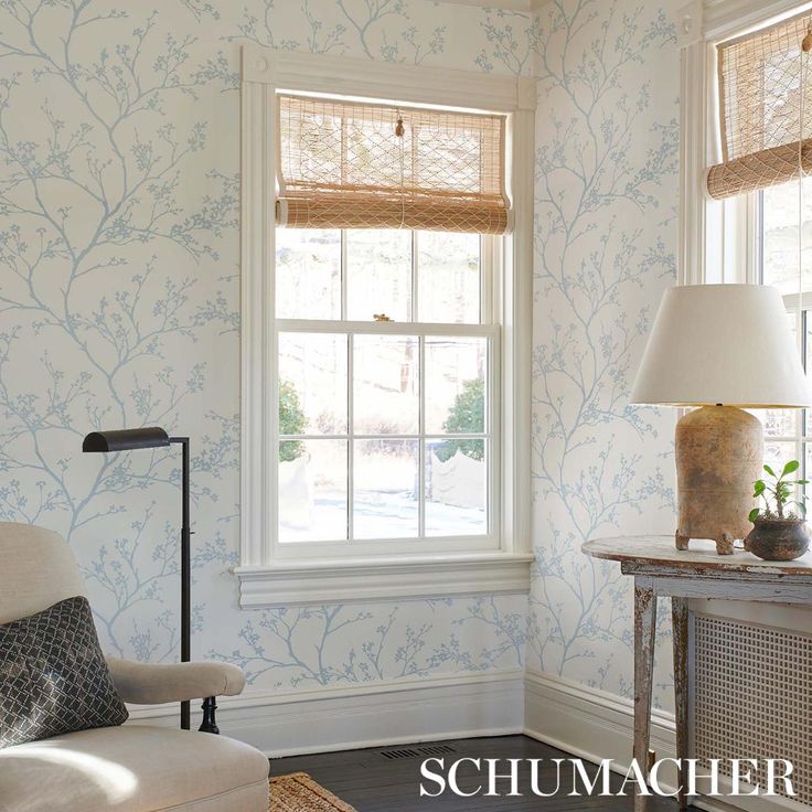 a living room with floral wallpaper and a chair in front of a large window