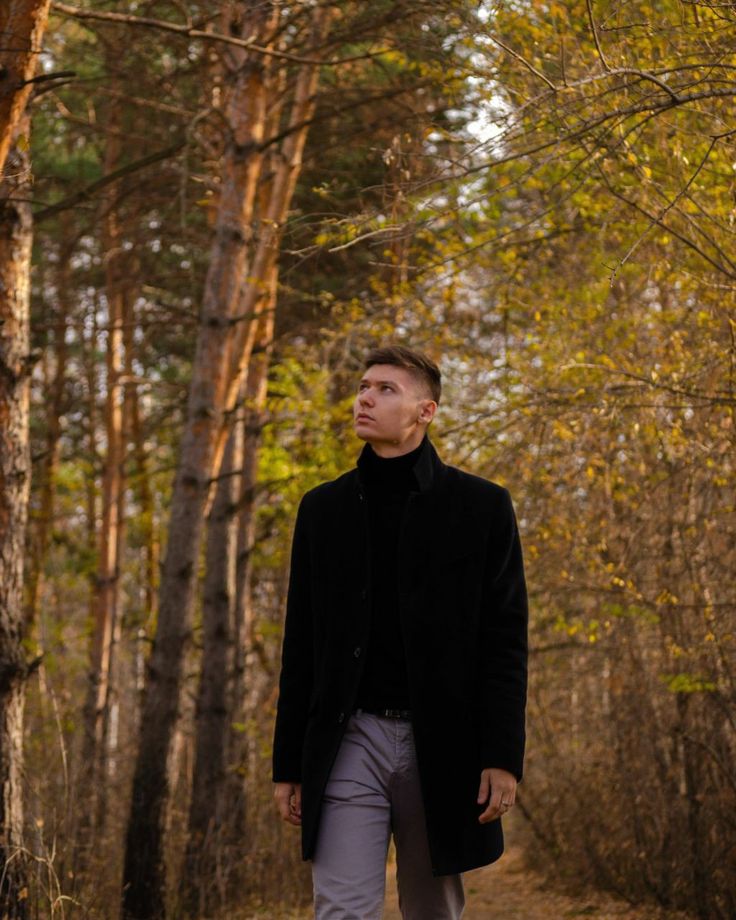 a man standing in the middle of a forest looking up into the sky with his eyes closed