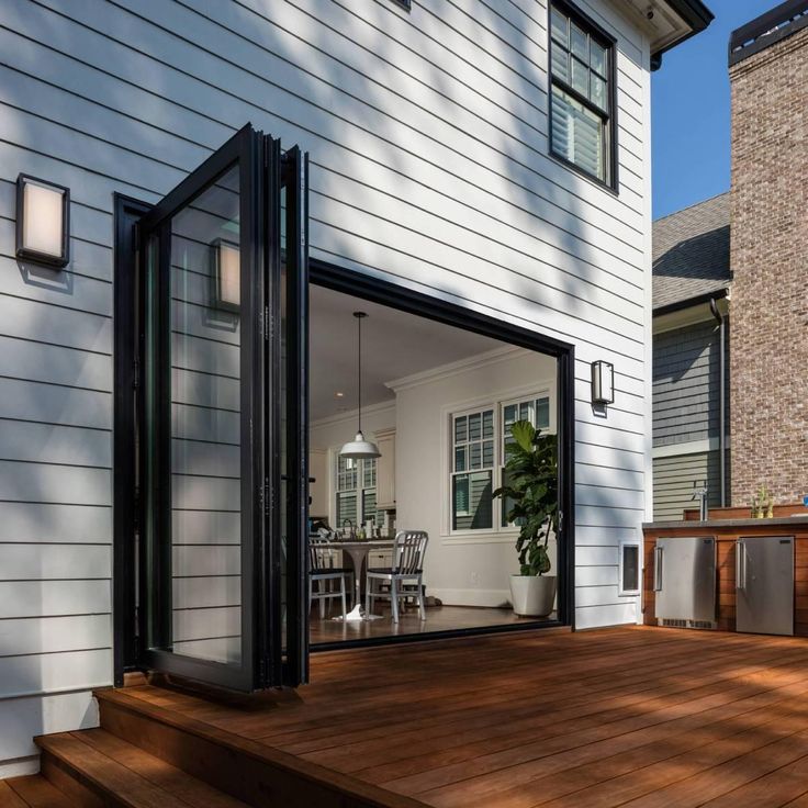 an open patio door on a house with wooden decking and white siding, overlooking the back yard