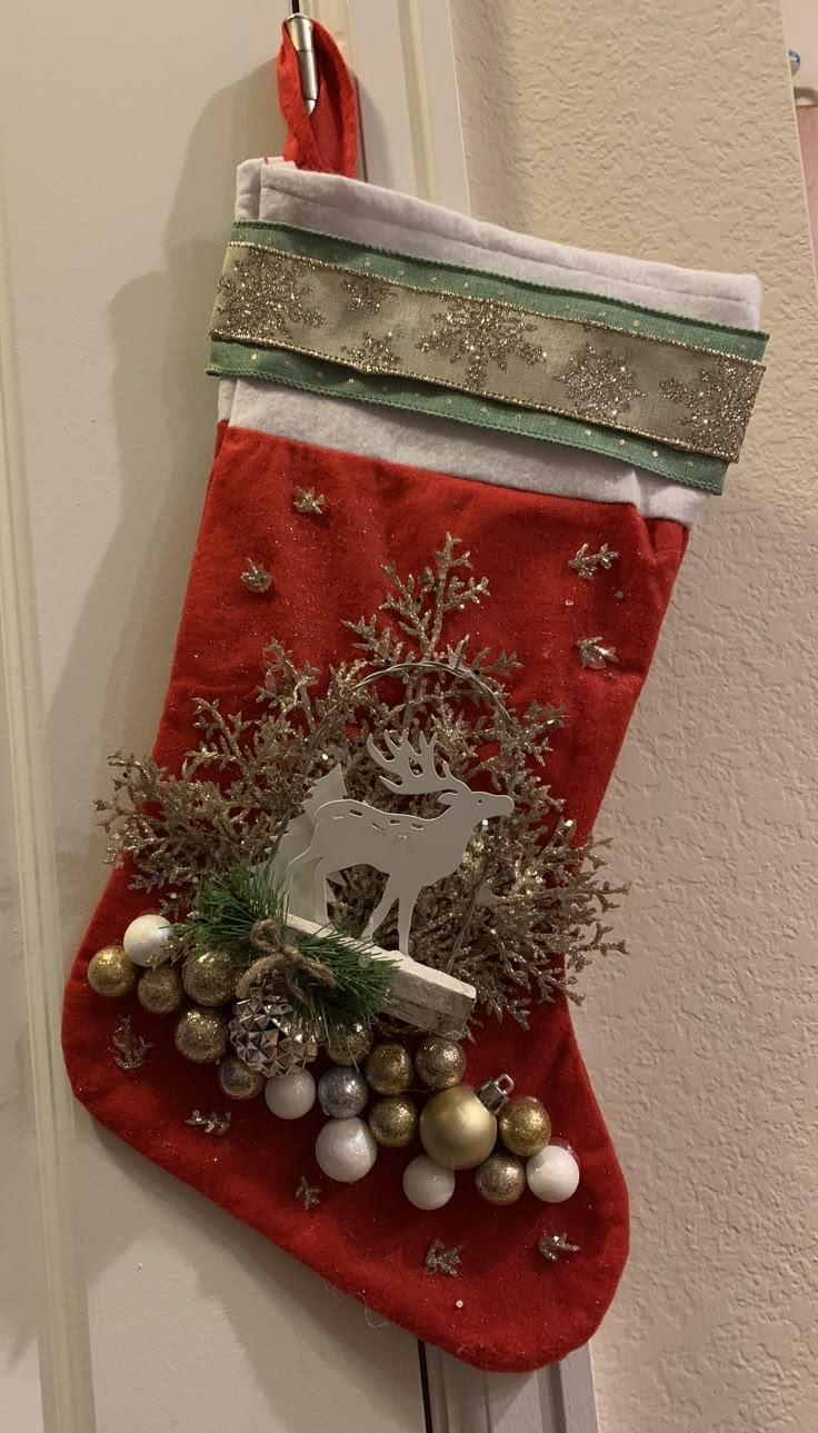 a christmas stocking hanging on the door with ornaments around it and a deer ornament