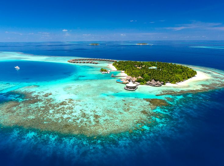 an island in the middle of the ocean surrounded by blue water and coral reefs