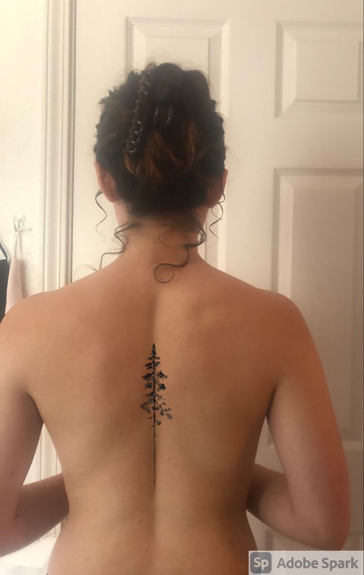 the back of a woman's body with a tree tattoo on her left side