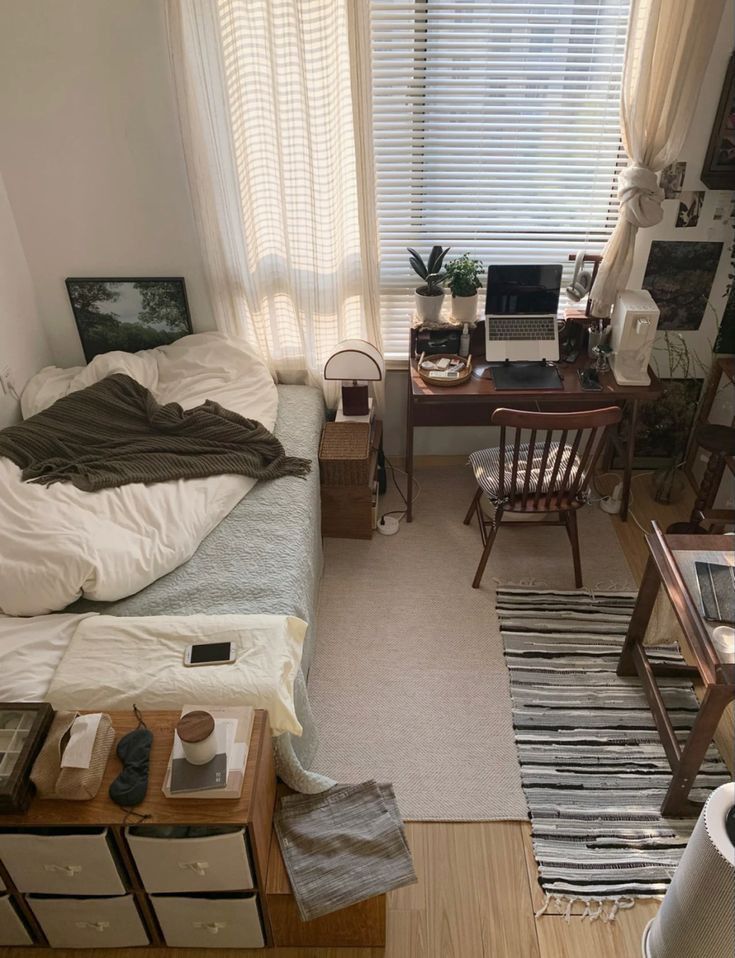 a bedroom with a bed, desk and chair in it's center area next to a window