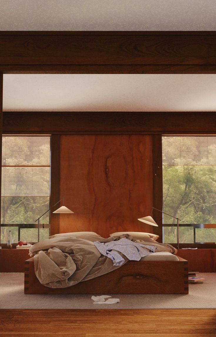 an unmade bed sitting in the middle of a room with wooden walls and windows