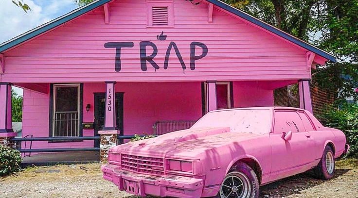 a pink car parked in front of a pink house with the word trap written on it