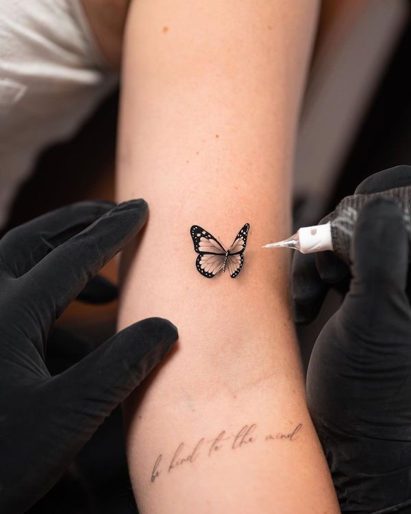 a woman getting a tattoo on her arm with a small butterfly on it's wrist