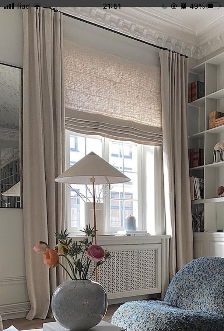 a living room filled with furniture next to a window covered in curtains and a lamp