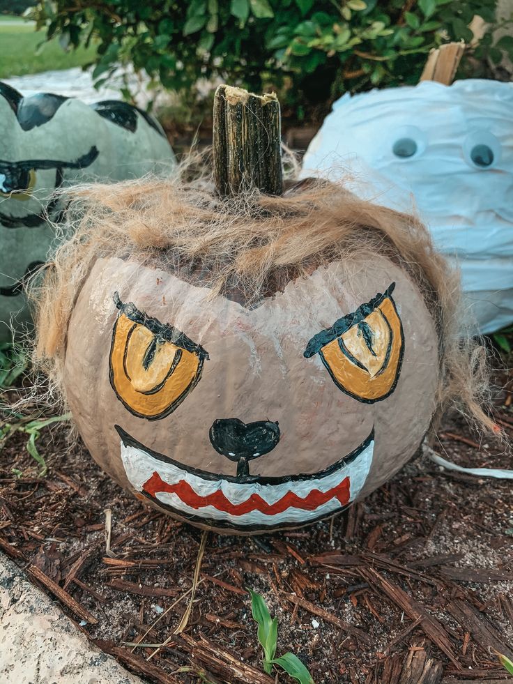 two painted pumpkins sitting on the ground next to each other