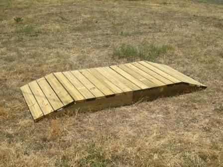 a wooden ramp laying on top of a dry grass field