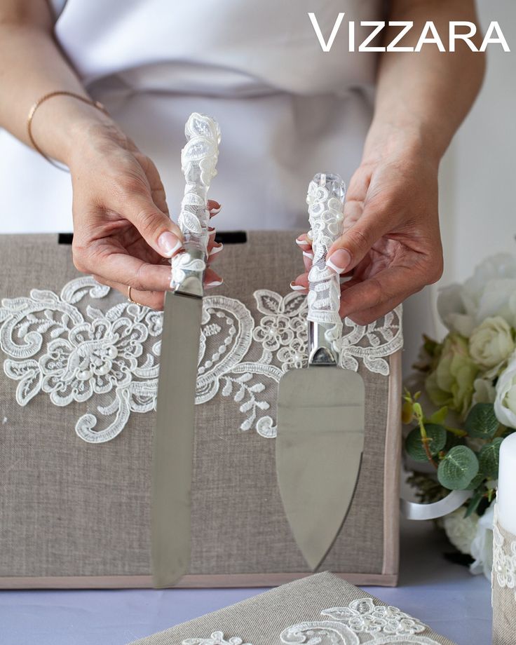 a woman is holding two knives in front of a box with white lace on it