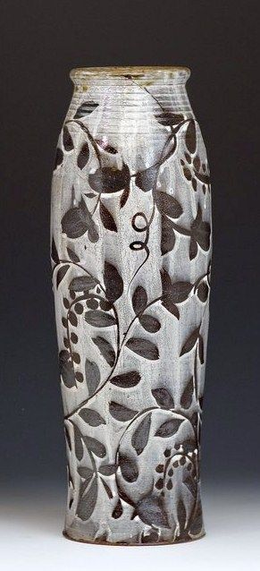 a white vase with black leaves on it