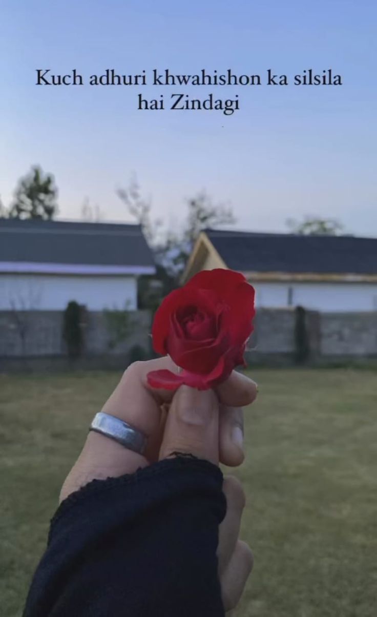 a person holding a red rose in their hand with the words kuch adrift khwashion ka silla hai zndag