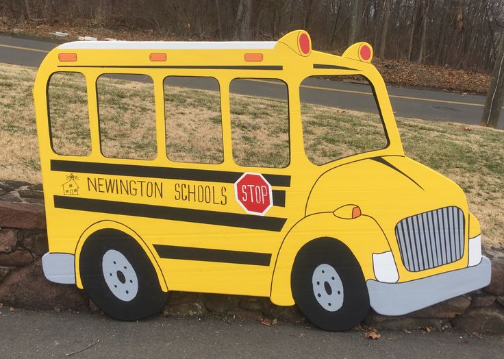 a cardboard school bus sitting on the side of a road next to a stone wall